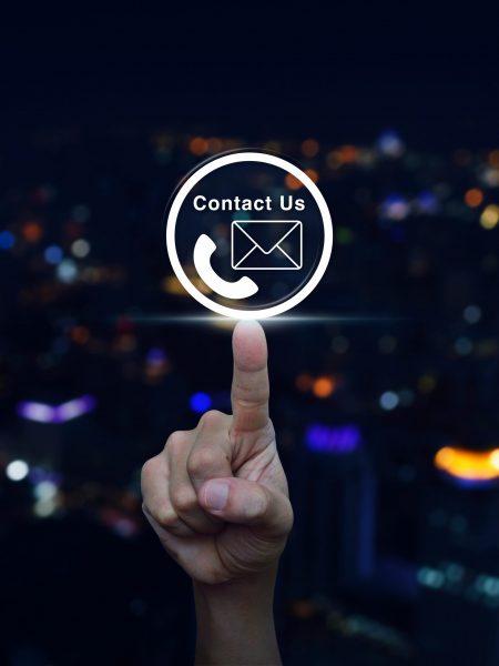 Hand pressing telephone and mail icon button over blurred light Hand pressing telephone and mail icon button over blurred light city tower background, Contact us concept